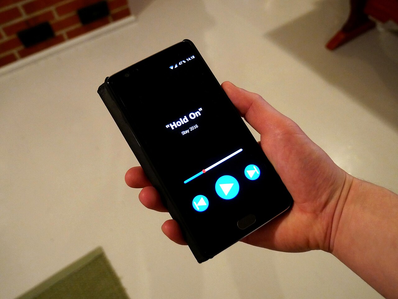 Hand holding a smartphone with a music player